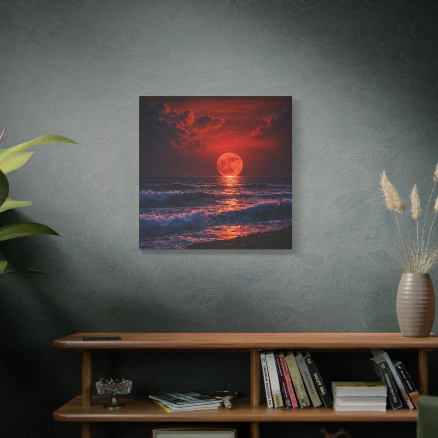 Room interior with a painting of a sunset over water on the wall, a wooden shelf with books and decor, and a plant.
