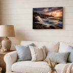 Living room with a couch, lamp, and wall art of a lighthouse at sunset.