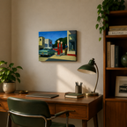 Home office with a desk, chair, lamp, and wall art of a gas station scene.